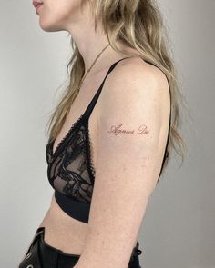 a woman with a small tattoo on her left arm and shoulder, standing in front of a white wall