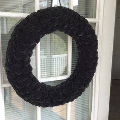 a wreath made out of rolled up black paper is hanging on the front door window