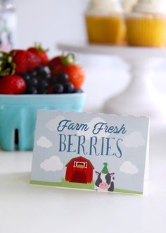 a sign that says farm fresh berries next to some strawberries and cupcakes