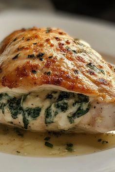 a white plate topped with chicken covered in sauce and spinach leaves on top of it