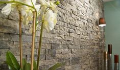 a vase with white flowers in front of a wall made of bricks and wood sticks