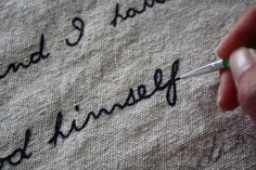 someone writing on a piece of fabric with a pen