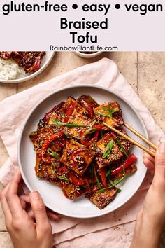 someone holding chopsticks over a plate of tofu