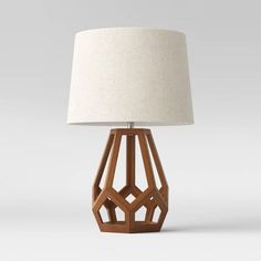 a wooden table lamp with a white shade on the top and bottom part of it