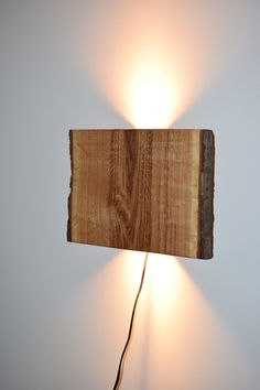 a light that is on the side of a wall next to a wooden block with a cord in it