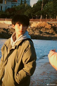 a young man standing on top of a beach next to the ocean