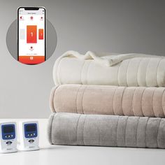 an alarm clock sitting on top of blankets next to two cell phones and one blanket