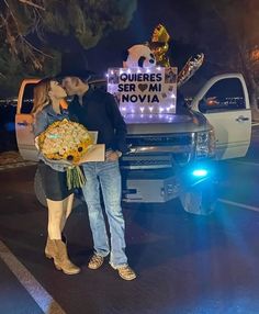 a man and woman kissing in front of a truck with sunflowers on it