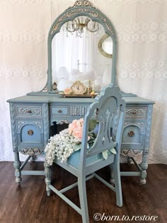 a blue dresser with a mirror and flowers on it