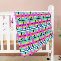 a baby crib with a pink, blue and green blanket on top of it