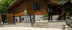 a wooden house with black iron railings and stone steps