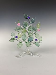 a glass figurine with leaves and flowers in it's center on a stand