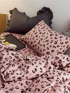 a bed covered in pink and black leopard print sheets with pillows on top of it