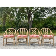 three chairs sitting in the middle of a gravel lot next to a tree and bushes