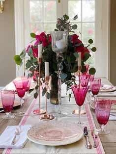 the table is set with pink glasses and plates