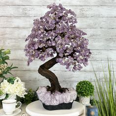 Large Handmade Amethyst Gemstone tree with a large and amazing Amethyst cluster base, resin trunk, wired branches and tumbled Amethyst gemstones. At approximately 25" tall with 144 branches and 720 gemstones, this gemstone tree is both big and a design statement that will impact any room, be that your living room or office. The amethyst clusters used as bases for this size of trees are substantial gemstones on their own. The process to make a gemstone tree like this is very extensive and meticulous. A special amethyst cluster is selected for the base, the resin trunk and branches are crafted by Brazilian artisans and then each gemstone is glued to the tree by hand. MADE IN BRAZIL! Height: 25.9" Width: 16" Depth: 13" Base Size: 10.1"W x 10"D x 5.2"H Weight: 40.2 lbs Shipping Note: This is a Spiritual Amethyst Gemstones With Accents, Amethyst Gemstones With Spiritual Style, Spiritual Amethyst Gemstones, Purple Amethyst Gemstones With Accents, Lavender Amethyst Gemstone Crystals, Spiritual Purple Gemstones With Accents, Gemstone Tree, Commitment Ceremony, Gemstone Meanings