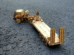 a wooden model of a semi - truck and tractor trailer in the middle of gravel