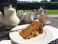 a piece of cake sitting on top of a white plate next to a cup and saucer