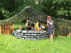 two men standing in front of a pile of sandbags on top of grass covered ground