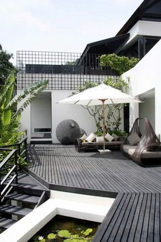 an outdoor deck with chairs and umbrellas next to a pond filled with water lilies