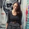 a woman standing in front of a graffiti covered wall