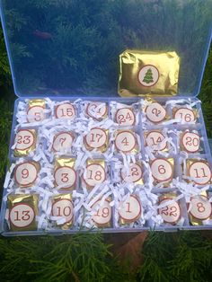 an open box filled with candy covered in white and gold wrappers next to evergreen branches