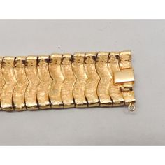 This is part of Chairish’s Costume Jewelry assortment.  Goldtone textured and smooth Asian inspired "waves" articulated bracelet with box clasp and security chain. Marked crown "TRIFARI." Measures: 7 1/4 inches long by 1 inch wide. Condition: Very good; light surface wear in places and a spot of goldtone loss to the back of part of the box clasp. An identical bracelet was featured in a 1959 advertisement. Metal Chain Bracelet With Clasp For Formal Occasions, Retro Yellow Gold Bracelet For Formal Occasions, Retro Yellow Gold Bracelets For Formal Occasions, Formal Metal Chain Bracelet With Clasp, Formal Gold Link Bracelet With Bracelet Strap, Yellow Gold Metal Bracelets With Box Clasp, Formal Metal Bracelets, Gold Jewelry With Clasp For Evening, Flexible Metal Bracelets For Formal Occasions