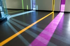 an empty room with bright colored lines on the floor and light coming through the windows