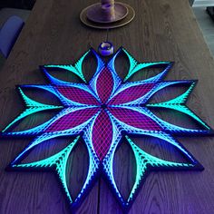 a wooden table with a purple and blue flower design on it, next to a candle holder