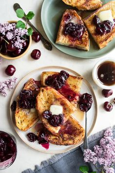 two plates topped with french toast and cherries