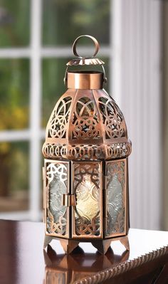 an ornate metal lantern sitting on top of a wooden table in front of a window