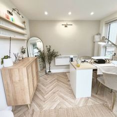 a room with a desk, chair and mirror in it that is white and wood