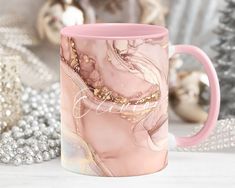 a pink coffee mug sitting on top of a table next to christmas decorations and ornaments