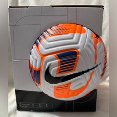 an orange and white nike soccer shoe is in a cardboard box on a table top