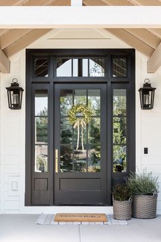 a black front door with two potted plants