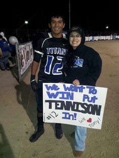 two people standing next to each other holding a sign