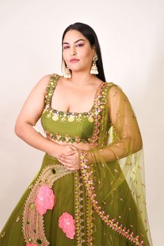 Introducing a tulle lehenga in olive, adorned with glass beads, metals, sequins, and 3D embroidered flowers. Paired elegantly with an olive raw silk blouse embellished with shell stones, crystals, and metals, along with a complementing tulle dupatta. This ensemble combines intricate detailing with a touch of glamour for a captivating look. Navratri Green Embellished Lehenga, Green Embellished Lehenga For Navratri, Embellished Green Lehenga For Navratri, Bollywood Style Embellished Green Anarkali Set, Anarkali Embellished Green Choli, Anarkali Style Embellished Green Choli, Green Embellished Anarkali Choli, Embellished Green Floor-length Choli, Green Embellished Traditional Wear For Reception