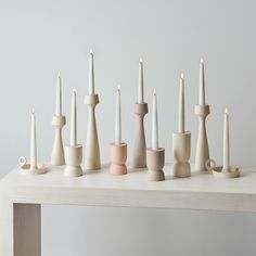 a group of white candles sitting on top of a wooden table next to each other