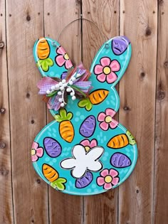 a painted easter bunny hanging on a wooden fence