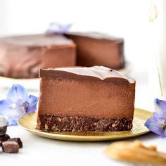 a slice of chocolate cheesecake on a gold plate with blue flowers next to it