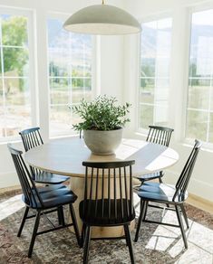 a dining room table with four chairs and a potted plant on the centerpiece