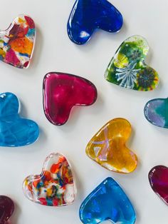 many different colored glass hearts on a white surface