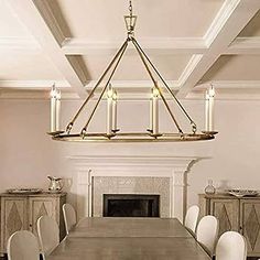 a chandelier hanging over a dining room table with white chairs and a fireplace