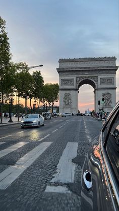 cars are driving down the street in front of an arc de trioe triumph gate