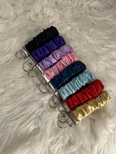 six different color satin headbands are lined up on a white fur surface