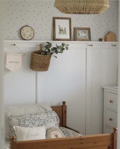 a baby crib in a bedroom with pictures on the wall and a basket hanging above it