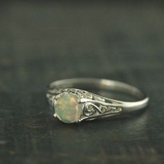 "\"If you keep on believing, the dream that you wish will come true\" Cinderella sparks memories of glass slippers, fairy god mothers, and dancing at midnight. This is her ring...dainty, intricate and as stunning as can be! A detailed filigree setting securely holds a 5mm rose cut Ethiopian Welo Opal. It is surrounded by intricate vining filigree. The top of the sterling silver ring measures nearly 6mm across tapering to a slim 1.5mm shank in the back. **Ethioian Welo Opals began entering the je Classic Hallmarked Silver Opal Ring, Silver Heirloom Opal Ring, Hallmarked, Sterling Silver Opal Ring, Fine Jewelry, Classic Sterling Silver Hallmarked Opal Ring, Sterling Silver Opal Ring In White Gold, Round Shape, November Birthstone Ring, Ethiopian Opal Ring, Glass Slipper, November Birthstone