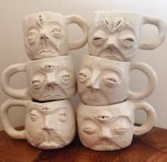 five white ceramic mugs with faces on them