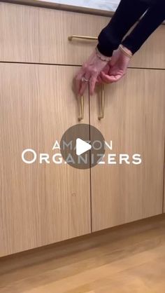 a person is holding onto the handles of a kitchen cabinet with wooden floors and cabinets