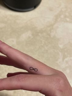 a woman's hand with a small tattoo on it and an infinite sign in the middle